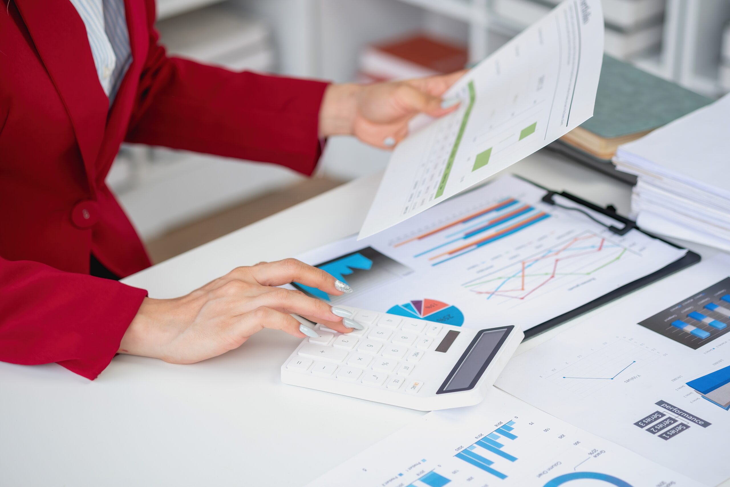 A woman's hands typing on a calculator while holding a document as she allocates her Recruitment Marketing Budget